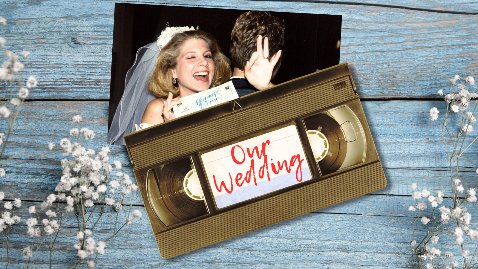 A worn VHS tape labeled “Our Wedding” sitting next to wedding keepsakes like a photo and pressed flowers