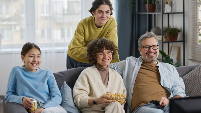 Family celebrating 50th birthday watching old memories digitized on screen