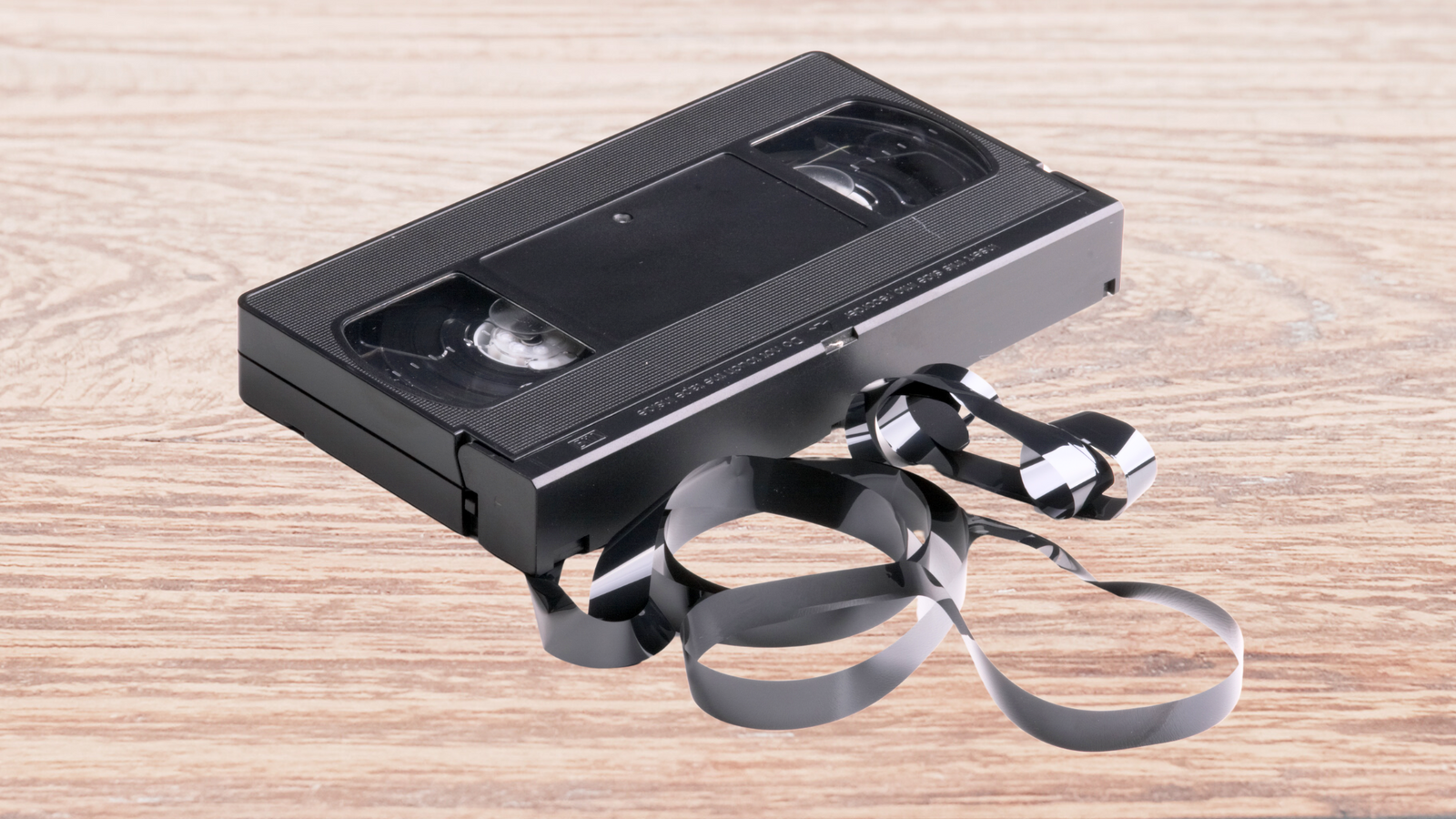 Old VHS Tape with Tangled Tape on Wooden Table
