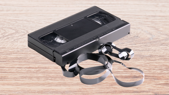 Old VHS Tape with Tangled Tape on Wooden Table