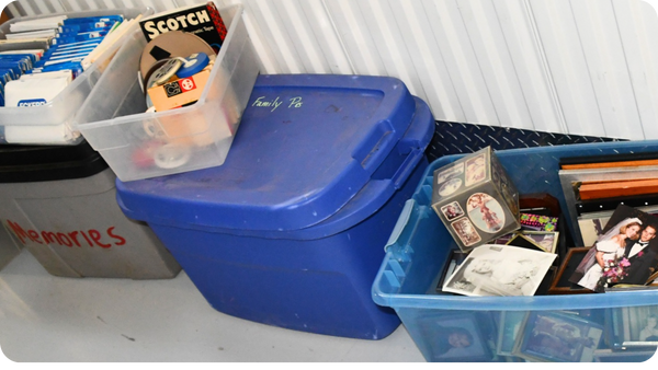 Boxes of old photos, VHS tapes, and home movie media stored together before digitizing