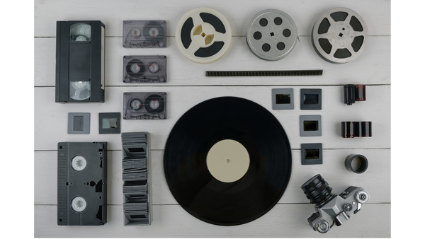 Neatly Arranged VHS Tapes, Photo Slides, Film Reels, Audio Cassette Tapes, and a Vinyl Record on a Wood Background