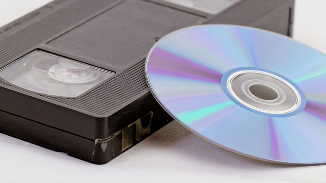 VHS tape and scratched DVD showing need for digital conversion