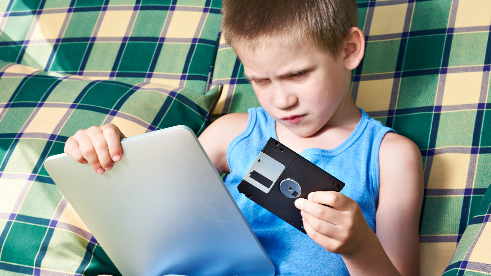 Boy holding floppy disk and modern compiting device