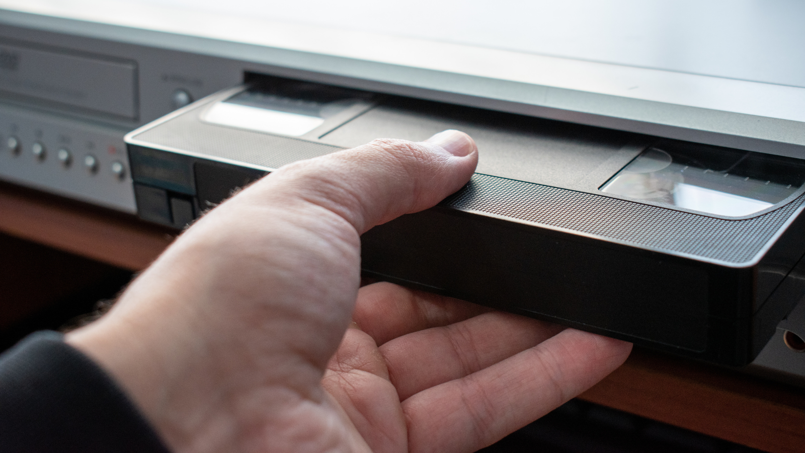 Close-up of inserting a VHS tape into an old VCR