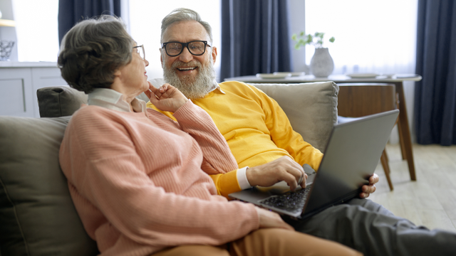 Couple watching old wedding video on laptop for anniversary gift