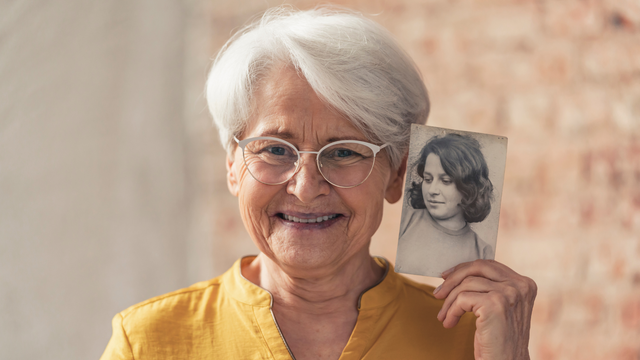 Elder woman holding photograph of herself as a child for scanning at 600 DPI