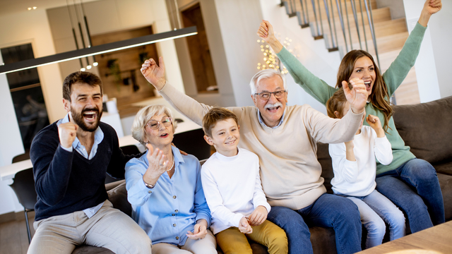 Family celebrating 60th birthday watching digitized home movies together