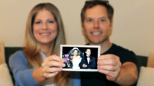 Married couple holding old wedding photo to be scanned at 600 DPI