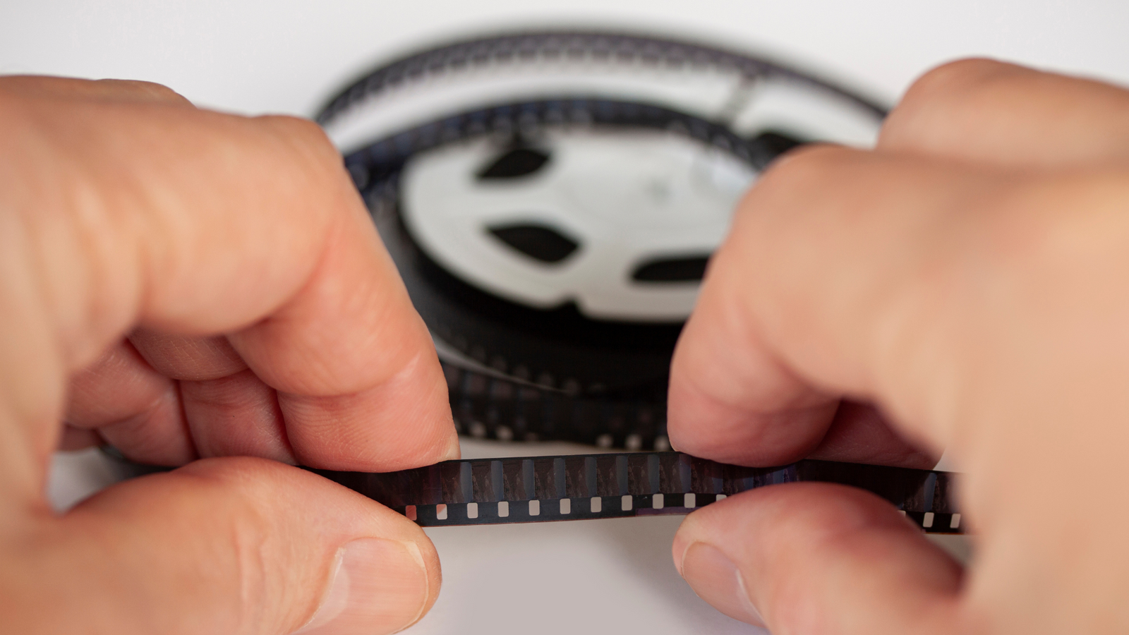 Hands holding an 8mm reel with no magnetic audio stripe