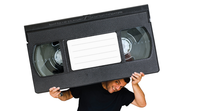 Man Burdened By an Oversize VHS Cassette Tape