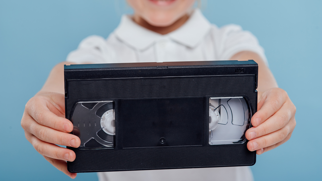Close-up of hands holding an aging VHS tape ready for preservation