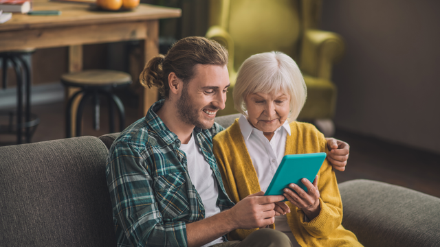 Mom and adult son scrolling through preserved family photos on a tablet