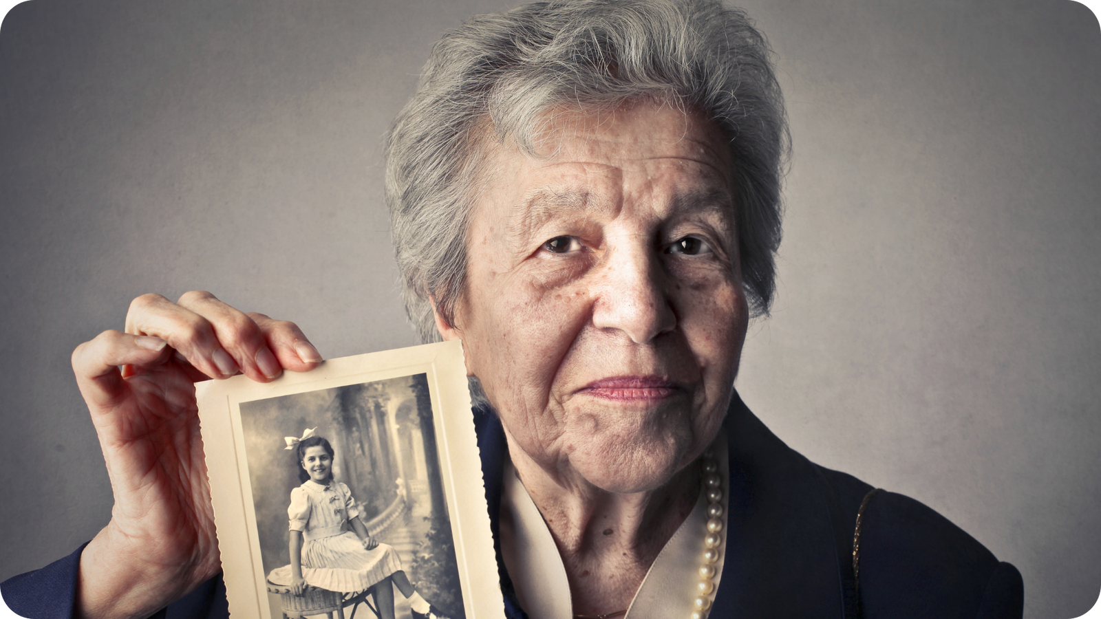 Woman holding old photograph of herself as a child before scanning at 600 DPI
