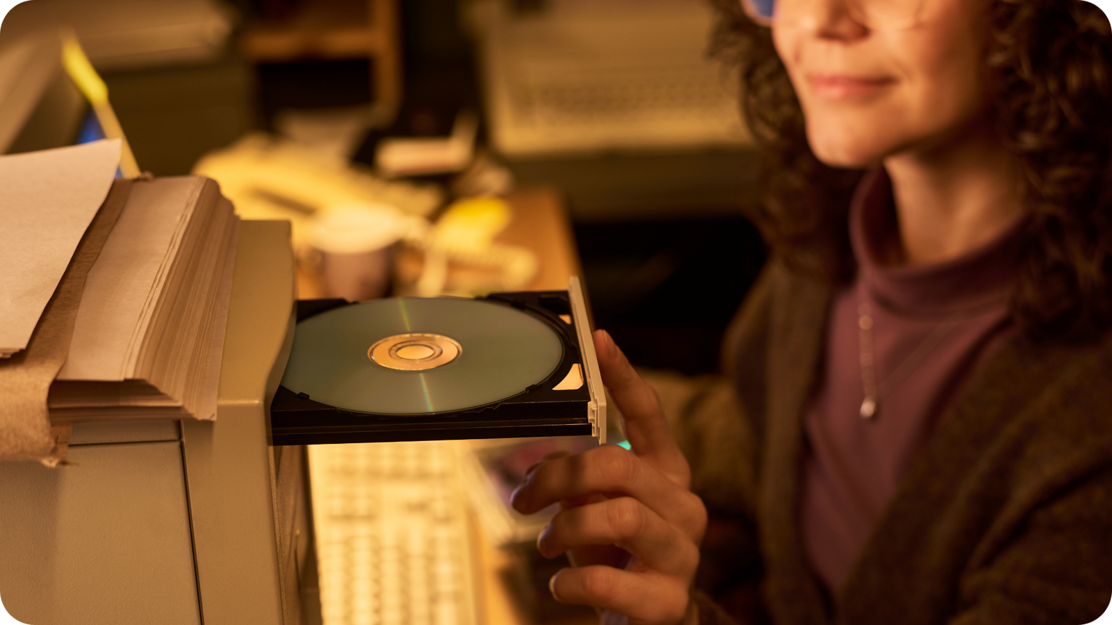 Woman putting a DVD into an old computer disc drive