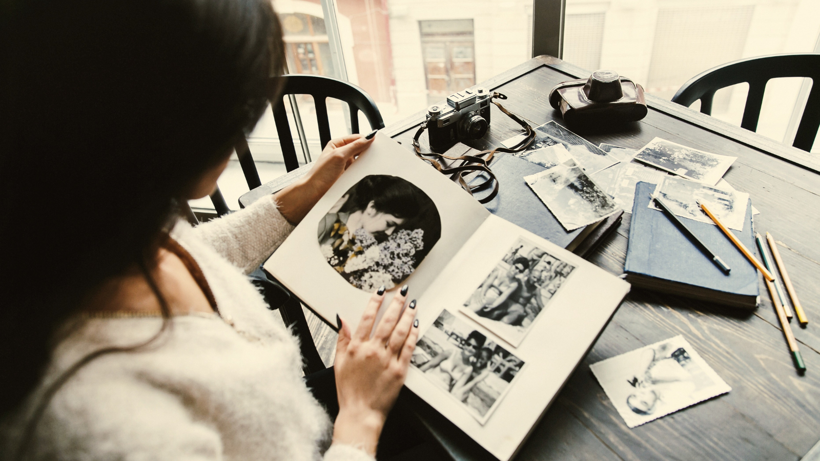 Woman reviewing printed photos and a photo album at home after Costco Photo discontinued in-store services.
