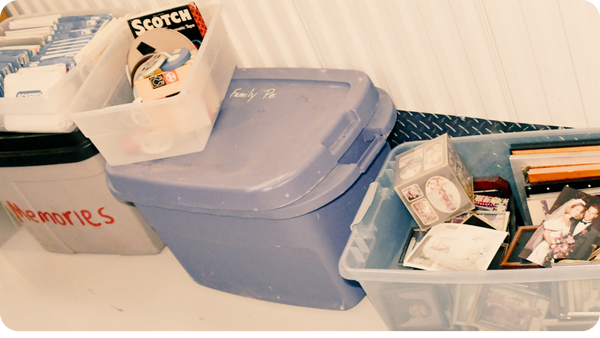 Boxes of old photos, VHS tapes, and home movie media stored together before digitizing